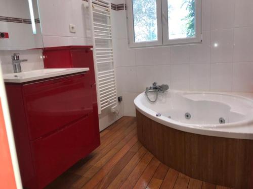a bathroom with a large tub and a red cabinet at La campagne dans l'Ocean à LA ROCHELLE les pieds dans la grange in Croix-Chapeau
