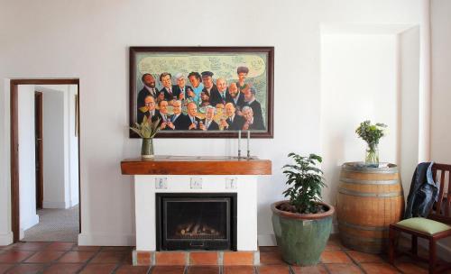 a fireplace in a living room with a framed picture on the wall at Jardin de la Ferme in Franschhoek
