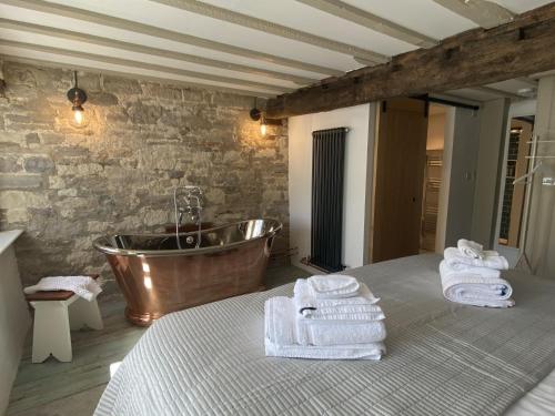 a bathroom with a tub and towels on a bed at Granary Cottage in Weymouth