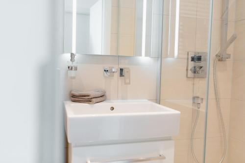 a white bathroom with a sink and a shower at SeaScape in Norderney