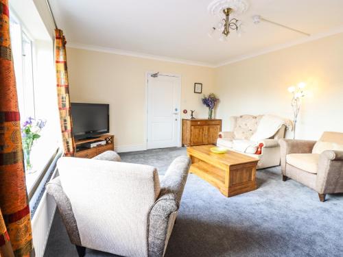 a living room with a couch and chairs and a tv at Maesbury Manor in Oswestry