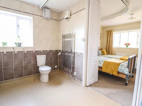a bathroom with a bed and a toilet in a room at Maesbury Manor in Oswestry