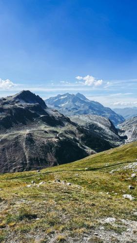 a view of a grassy hill with mountains in the background at Appartement esprit chalet - splendide vue montagne à 180 in Val dʼIsère