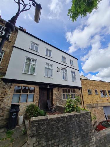 uma grande casa branca com um edifício de tijolos em The Old Church House top floor in private house central Frome em Frome