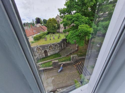 uma janela com uma pessoa sentada nos degraus de um edifício em The Old Church House top floor in private house central Frome em Frome