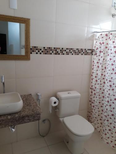 a bathroom with a toilet and a sink and a mirror at Pousada Frei Galvão in Cachoeira Paulista