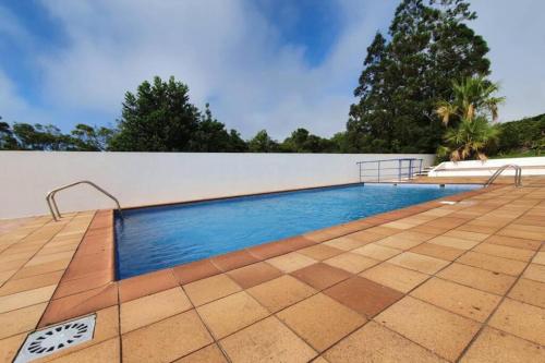 a swimming pool with a tile floor and a white wall at Casa dos Amigos in Ponta Delgada