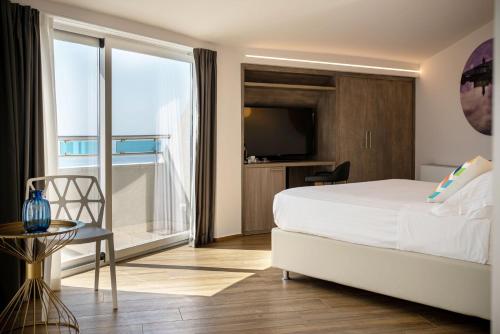 a bedroom with a white bed and a large window at Grand Hotel Faraglioni in Acitrezza