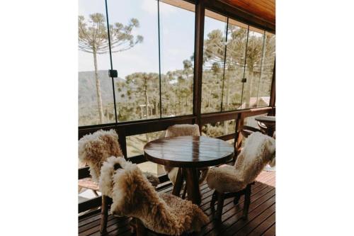 a room with a table and chairs and windows at Morada nas Montanhas Chale 08 in Urubici