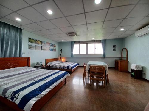 a bedroom with two beds and a table and chairs at Smile house Homestay in Taiping