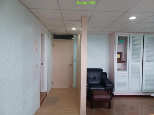 a hallway with a black leather chair in a room at Smile house Homestay in Taiping