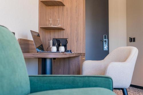 a room with two chairs and a table with a laptop at Hotel D Bulle - La Gruyère in Bulle