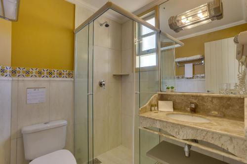 a bathroom with a shower and a toilet and a sink at Villas Jurerê Hotel Boutique in Florianópolis