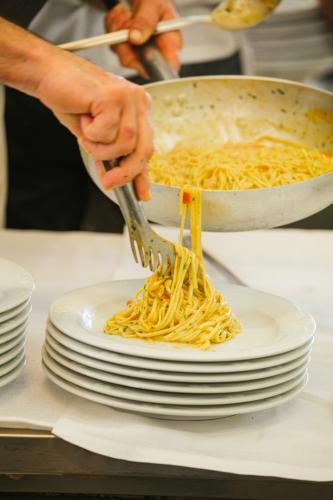 a person holding a fork over a plate of pasta at Hotel Bristol in Lido di Jesolo