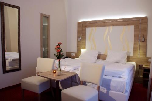pokój hotelowy z łóżkiem, stołem i krzesłami w obiekcie Royal Marianske Lazne w Mariańskich Łaźniach