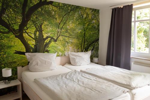 two beds in a bedroom with a tree mural on the wall at Hof Timmermann - Landhaus, oben in Ottenstein