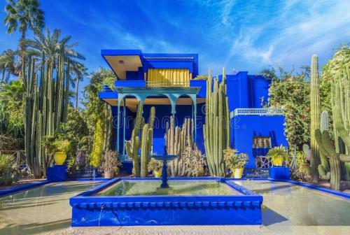 a blue building with a fountain in a yard with cactus at Bonheur Partagé 2chambres in Marrakech