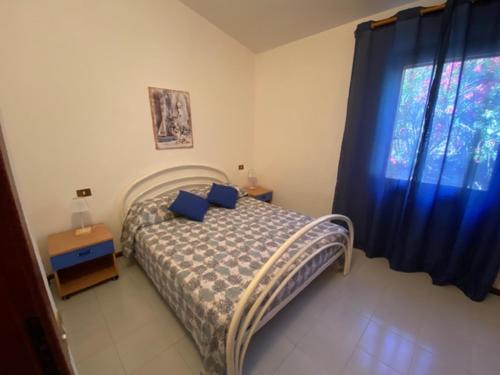 - une chambre avec un lit doté d'oreillers bleus et d'une fenêtre dans l'établissement Villa Chiara a 100 mt dalla spiaggia, à Stintino
