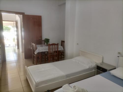 1 dormitorio con 2 camas, mesa y sillas en Baci Apartments, en Ksamil