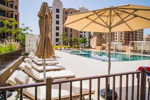a group of lounge chairs and an umbrella next to a pool at Stunning, Upgraded 2-BR Apartment in Lamtara 2 MJL Burj Al Arab View in Dubai