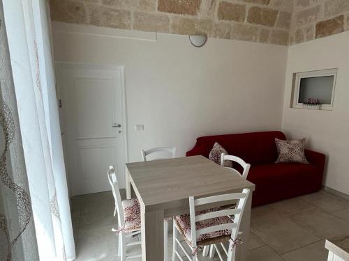 a table and chairs in a living room with a red couch at Donna Maria Pina in Monopoli