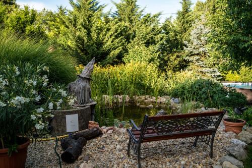 a bench in a garden with a pond and trees at Vendégház a hegyen in Budapest