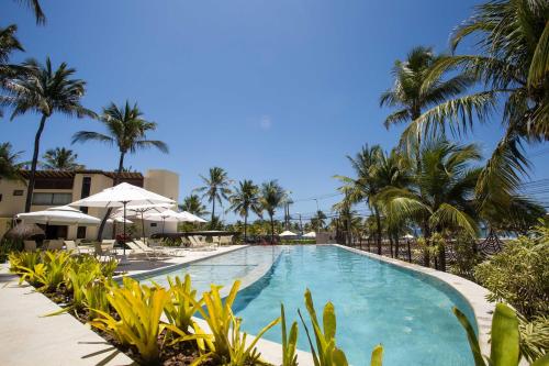 uma piscina no resort com palmeiras e guarda-sóis em CASA Di VINA Boutique Hotel em Salvador