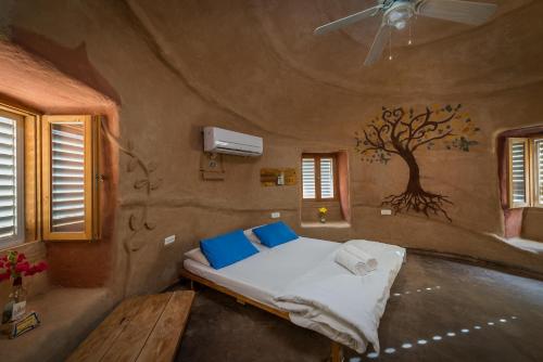 a bed in a room with a tree painted on the wall at Kibbutz Lotan Eco-Campus 