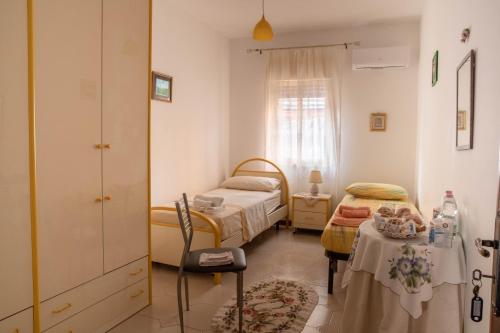 Habitación pequeña con 2 camas y mesa. en B&B Chiaro di Luna en Corleone