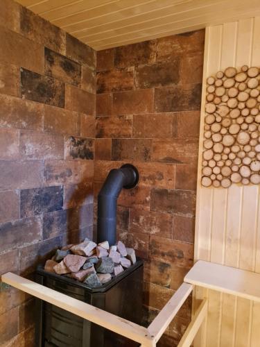 a brick wall with a wood stove in a room at Atostogų namelis-pirtis Prie upės in Anykščiai
