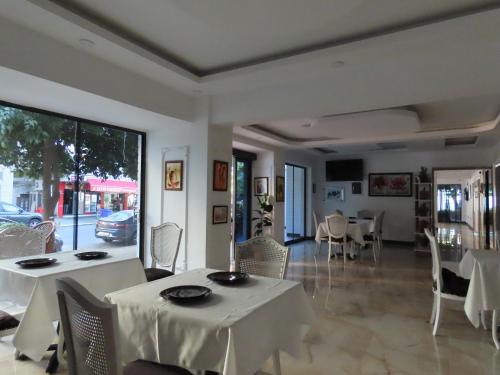 uma sala de jantar com mesas e cadeiras brancas e uma janela em Kadeer Hotel em Alanya