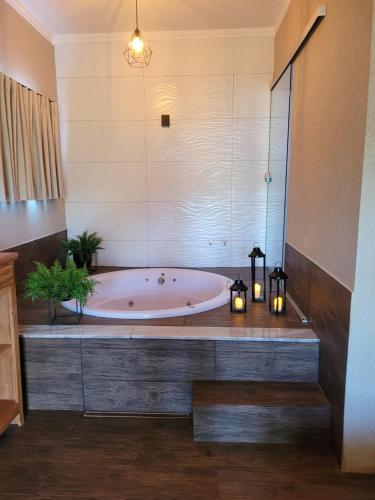 a bath tub in a bathroom with two candles and lights at Pousada Lago Azul in Delfinópolis