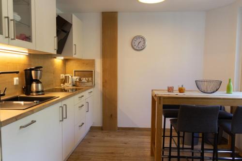 una cocina con armarios blancos y una mesa con taburetes. en Hof Timmermann - Landhaus, unten, en Ottenstein