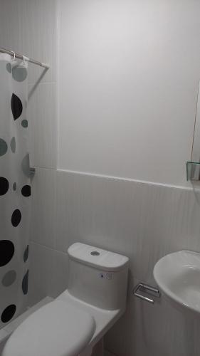 a white bathroom with a toilet and a sink at Hospedaje Margarita in La Merced