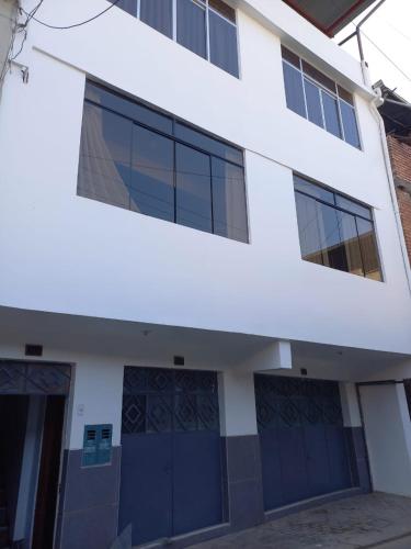 a white building with blue doors and windows at Hospedaje Margarita in La Merced