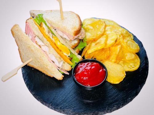 a sandwich and chips on a black plate with ketchup at The Wind Mills Hydropark in Gorna Malina