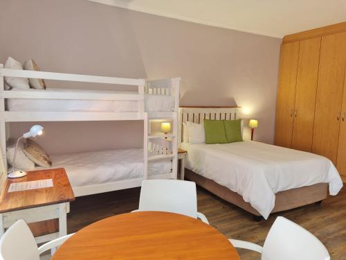 ダーバンヴィルにある10 Windell Self Catering Accommodationのベッドルーム1室(二段ベッド2組、テーブル付)