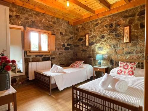a bedroom with two beds and a stone wall at Casa Rural Puerto del Escudo in Cilleruelo de Bezana