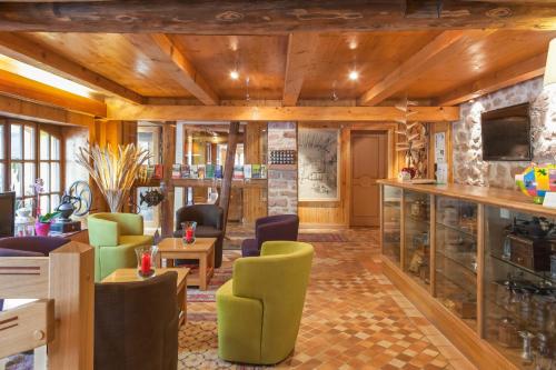 Elle comprend un salon doté de plafonds en bois et de chaises vertes. dans l'établissement Auberge La Meuniere, à Thannenkirch