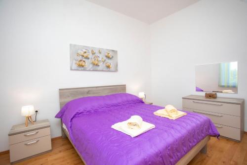 a bedroom with a purple bed with hats on it at Apartman Lidija Koromačno in Koromačno