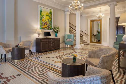 a lobby with chairs and a television and a staircase at Taplow House Hotel & Spa in Maidenhead
