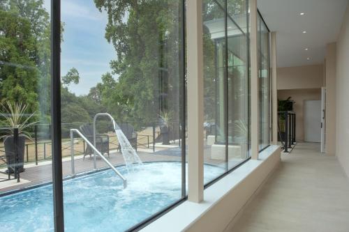 a swimming pool in a house with glass windows at Taplow House Hotel & Spa in Maidenhead