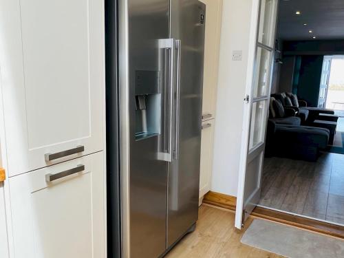 a stainless steel refrigerator in a kitchen with a living room at Pass the Keys Fabulous Beach Front Holiday Location in Lydd