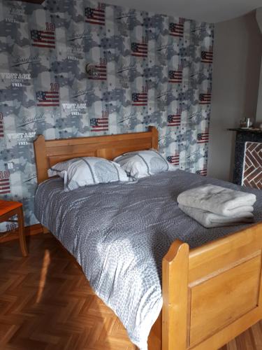 Ce lit se trouve dans une chambre dotée de papier peint américain. dans l'établissement DEUX CHAMBRES DANS UNE MAISON INDIVIDUELLE AU COEUR De L AVESNOIS, à Saint-Hilaire-sur-Helpe