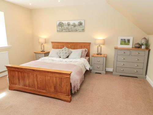 a bedroom with a wooden bed and two night stands at Calm Skies in Berwick-Upon-Tweed
