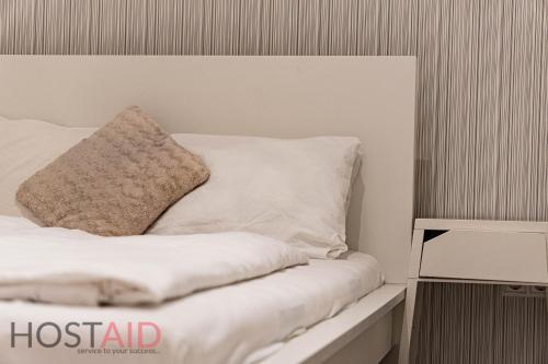 uma cama com lençóis brancos e uma almofada em A5 Apartment - Budapest - hostAID em Budapeste