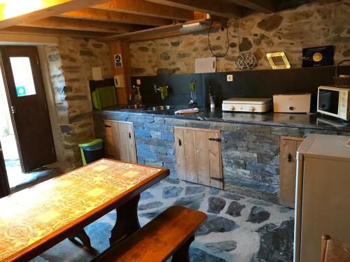 a kitchen with a wooden table and a stone wall at Casa Capela - Casas do Sinhel in Alvares