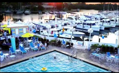 a pool with tables and chairs and boats in a marina at Remodeled, Huge Pool, Tiki Bar & Grill, Quiet Room in Sarasota