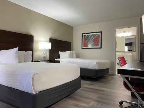 a hotel room with two beds and a desk at Remodeled, Huge Pool, Tiki Bar & Grill, Quiet Room in Sarasota