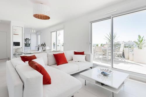 a white living room with a white couch and red pillows at Antibes Juan in Antibes